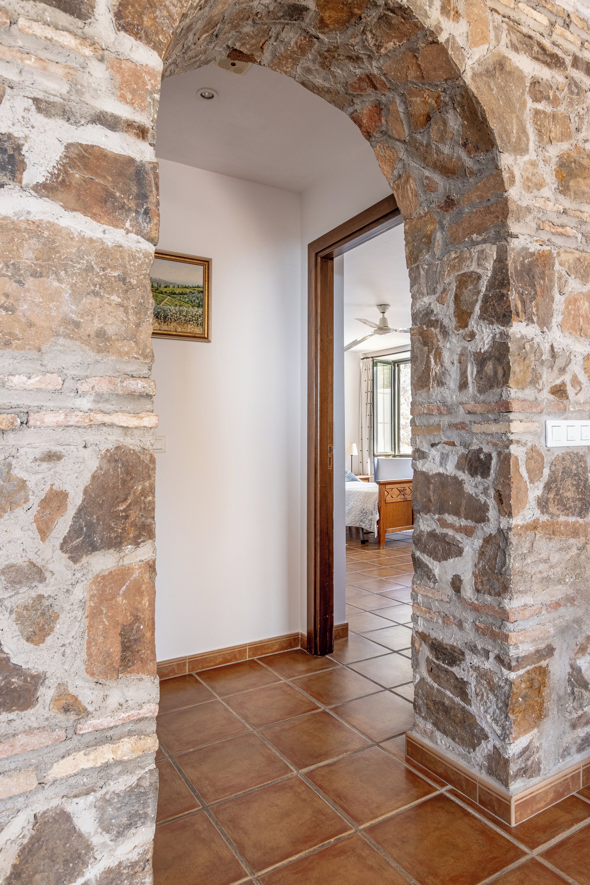 An interior hallway with stone walls, a tiled floor, and a door leading to another room.