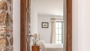 A bedroom with a bed, bedside lamps, a framed picture, and a window with curtains. - Jasmine Padre Aviles 17th C converted convent with pool, tennis & amazing views (Malaga)