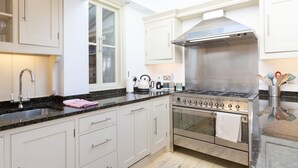 Une cuisine moderne avec des meubles blancs, une cuisinière en acier inoxydable et une grande fenêtre.