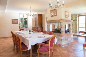 Comedor con chimenea de ladrillo, sillas de madera y una araña.