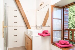 Un baño con ducha, lavabo y ventana.