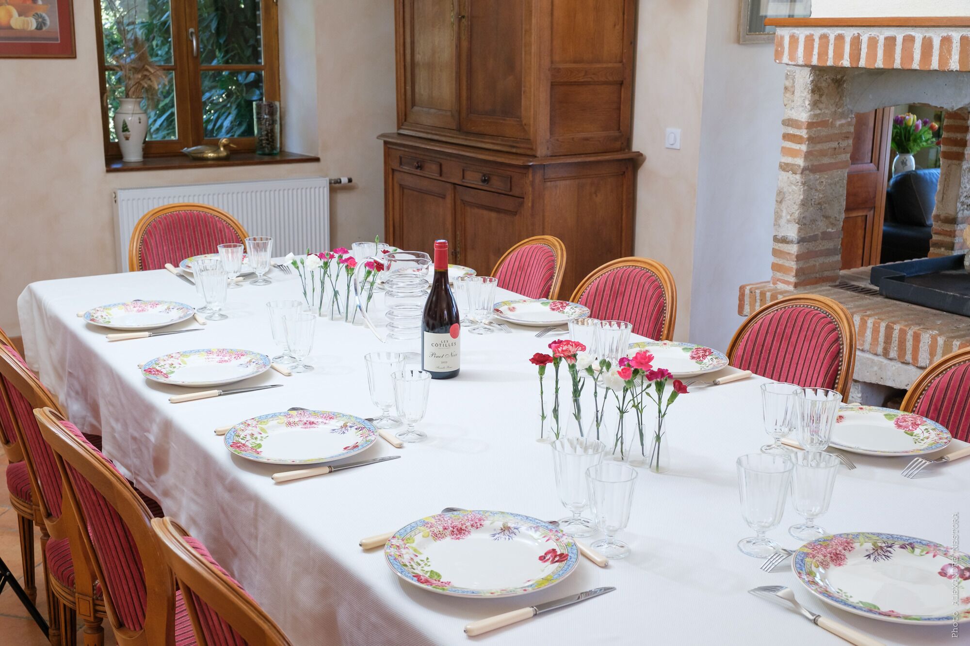 Una mesa de comedor lista para una comida, con mantel floral, platos y cristalería.