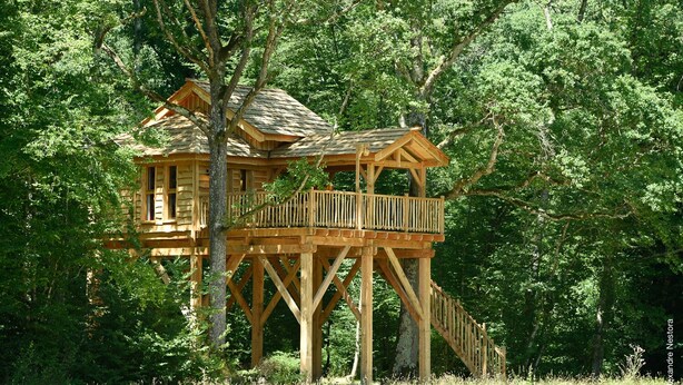 Una casa árbol de madera con balcón y escalera.