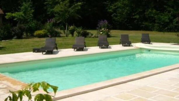 A swimming pool with lounge chairs and a garden area.