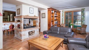 Una sala de estar con chimenea, sofás de cuero, una mesa de centro con flores y una estantería.