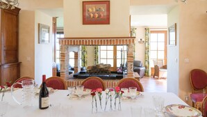Comedor con chimenea de ladrillo, una mesa preparada para seis comensales y una araña.