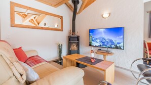 A cozy living room with a sofa, a wooden coffee table, a television, and a fireplace.