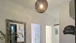 A modern hallway with a wooden desk, a mirror, a potted plant, and a ceiling light fixture. - Apartment on the Beach Malvarrosa Cabañal, CA MICAELA- Wifi free, easy parking (València)