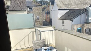 A rooftop terrace with a table set for four, surrounded by wicker chairs, overlooking a residential area with stone buildings. - Lobster Pot in Padstow Is A 'fisherman's Style' Cottage With A Parking Space. (Padstow)