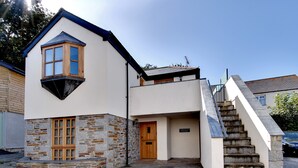 A two-story building with a stone facade, a wooden door, and a staircase leading to the upper floor. - Lobster Pot in Padstow Is A 'fisherman's Style' Cottage With A Parking Space. (Padstow)