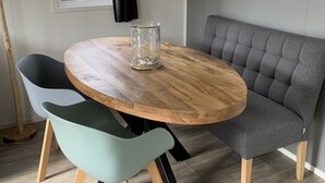 A dining area with a round wooden table, two chairs, a bench, and a floor lamp.