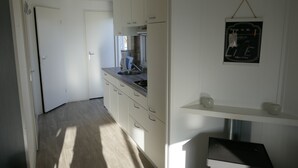 A narrow kitchen with white cabinets, a stove, and a hanging sign.