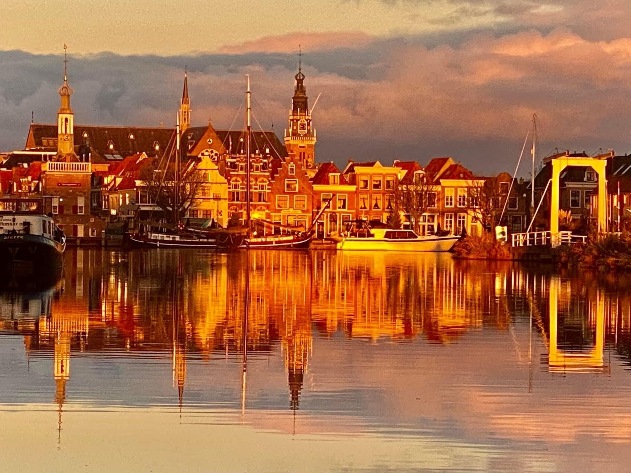 A waterfront town with historic buildings, a prominent church tower, and a bridge.
