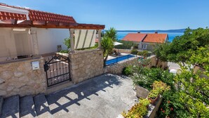 Une propriété située sur la côte, dotée d’un mur en pierre, d’un portail en métal, d’une petite piscine et offrant une vue sur la mer.