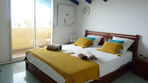 A bedroom with a bed, a nightstand, a window, and a door. - Family villa Koris Coquillages - swimming pool - near Sainte-Anne beaches  (Sainte Anne)