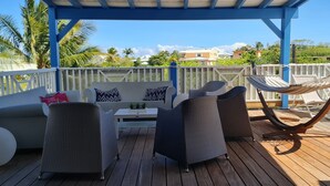 A covered outdoor seating area with wicker furniture, a hammock, and a view of the surrounding landscape. - Family villa Koris Coquillages - swimming pool - near Sainte-Anne beaches  (Sainte Anne)