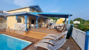 A poolside area with a pool, lounge chairs, and a covered patio. - Family villa Koris Coquillages - swimming pool - near Sainte-Anne beaches  (Sainte Anne)