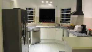 A modern kitchen with white cabinets, a built-in oven, and a black range hood. - Family villa Koris Coquillages - swimming pool - near Sainte-Anne beaches  (Sainte Anne)