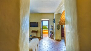 A hallway leading to a balcony with a TV, a small table, and a bookshelf. - Lovingly renovated Fisherman's cottage « Luazinha » (Tavira)