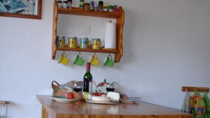 Ein Holzespeisetisch mit Bänken, ein oberes Regal mit Gläsern und Tassen, und ein hängender Kleiderständer.