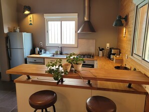 Een keuken met een centraal eiland, een koelkast, een raam en een fornuis.