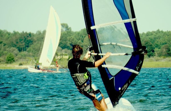Una persona practicando windsurf en el agua con una vela.