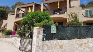 A two-story building with balconies, a stone wall, and a gate. - Nice studio, spacious, air-conditioned, near village, sea view in small residence. (Cargèse)