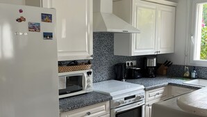 Une cuisine moderne avec des meubles blancs, un four à micro-ondes, une cuisinière et un réfrigérateur.
