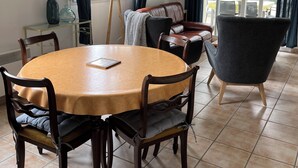 Un espace repas comprenant une table ronde, des chaises en bois, un canapé et un fauteuil moderne.
