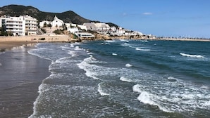 A coastal beach with buildings in the background. - BALMINS APARTMENT, FULLY EQUIPPED 50 MTS FROM THE BEACH OF ST.SEBASTIA (SITGES)