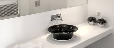 A modern bathroom with a white vanity, a black sink, and a large mirror.