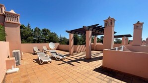 Eine Dachterrasse mit Liegestühlen, einer Pergola und einem Poolbereich.
