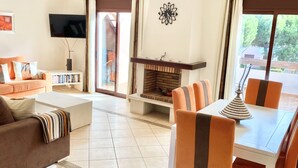 Ein Wohnzimmer mit einer Couch, einem Couchtisch, einem Kamin und einem Essbereich mit Stühlen und Tisch.