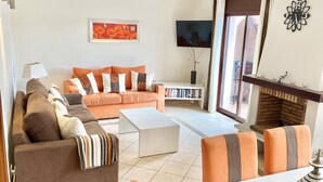 Ein Wohnzimmer mit einer Sofagarnitur, einem Couchtisch, einem Fernseher, einem Kamin und einem Bücherregal.