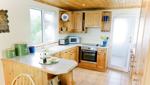 Eine Küche mit Holzausstattung, einer zentralen Kochinsel, einer Mikrowelle, einem Backofen und einem Spülbecken.