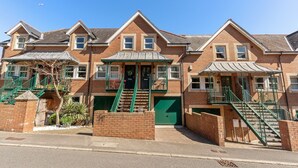 Une rangée de maisons en briques, avec des escaliers verts et un petit porche.