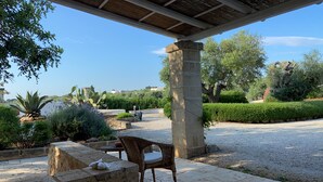 A covered outdoor seating area with a stone pillar, a wicker chair, and a table. - Wonderful "Trullo Saraceno" (Ostuni)