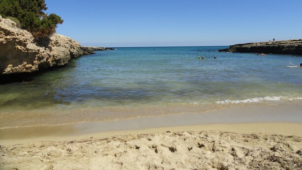 A beach with clear water, sandy shore, and rocky cliffs. - Wonderful "Trullo Saraceno" (Ostuni)