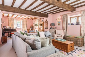 Une pièce chaleureuse avec un piano, un canapé, un panier en osier et une malle en bois.