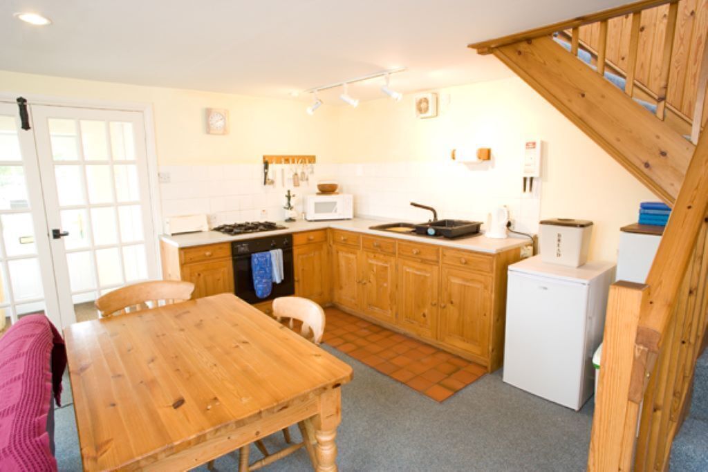 A compact kitchen with wooden cabinets, a microwave, a stove, and a small refrigerator.