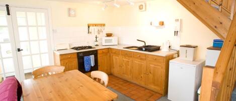 A compact kitchen with wooden cabinets, a microwave, a stove, and a small refrigerator.