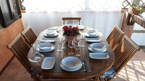 A round wooden dining table set with white plates, glasses, and a vase of red flowers. - Sa Domu De Sa Murta 1B: 200 mtr to Baia Marina!!! Free Bikes & Kayaks. IUN P2964 (Torre di Bari)