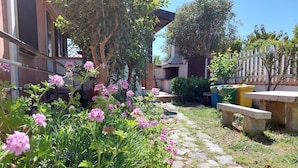A garden with stone pathway, flowering plants, and a bench. - Sa Domu De Sa Murta 1B: 200 mtr to Baia Marina!!! Free Bikes & Kayaks. IUN P2964 (Torre di Bari)