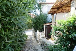 Stroll along the cobblestone path to a charming, rustic retreat surrounded by lush greenery and a stone wall.