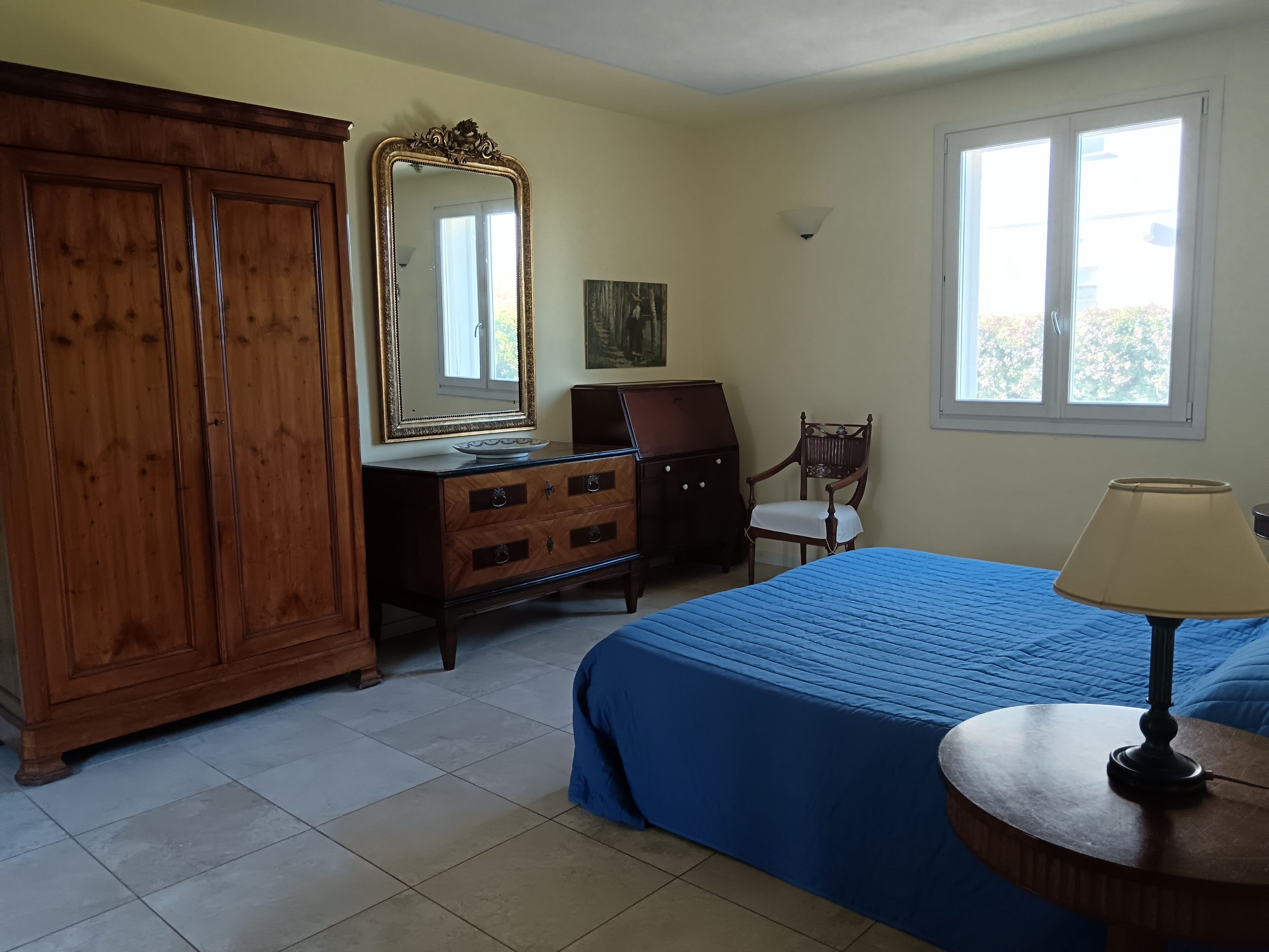 Une chambre à coucher avec un lit, une commode, une chaise et une lampe.