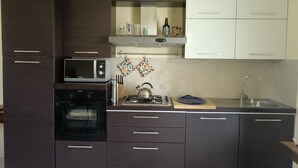 Una cucina moderna con mobili marrone scuro, un forno a microonde, un forno, un piano cottura a gas e un lavello.