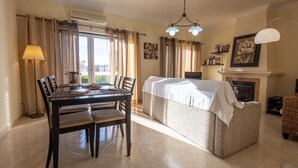 A dining area with a table and chairs, a sofa, a lamp, and a fireplace. - Casa Mateus (Alvor)