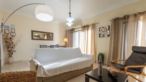 A well-lit room with a large bed, a chair, a table, and a mirror on the wall. - Casa Mateus (Alvor)