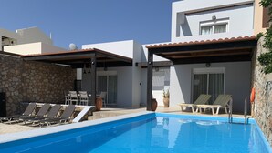 A swimming pool with lounge chairs and a stone wall. - Beautiful villa with private pool & garden and stunning views of Navarone Bay. (Lindos)