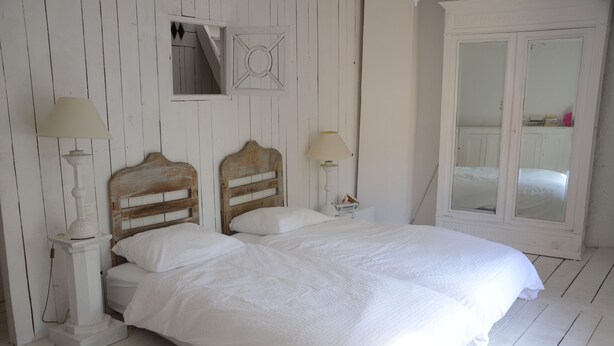 A bedroom with a wooden headboard bed, two bedside tables with lamps, and a white wardrobe. - charming fisherman house (Gruissan)